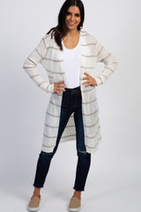 woman wearing a white and tan striped long cardigan with dark blue jeans and tan slip-on shoes