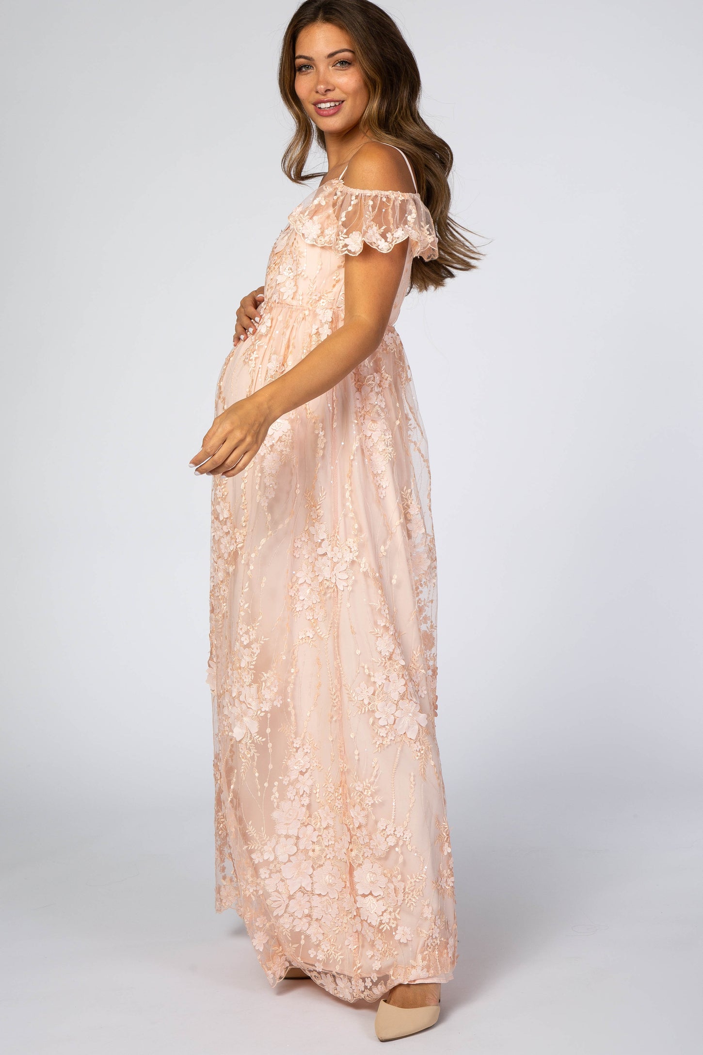 pregnant woman in a light pink floral lace maternity maxi dress with off-the-shoulder ruffle sleeves