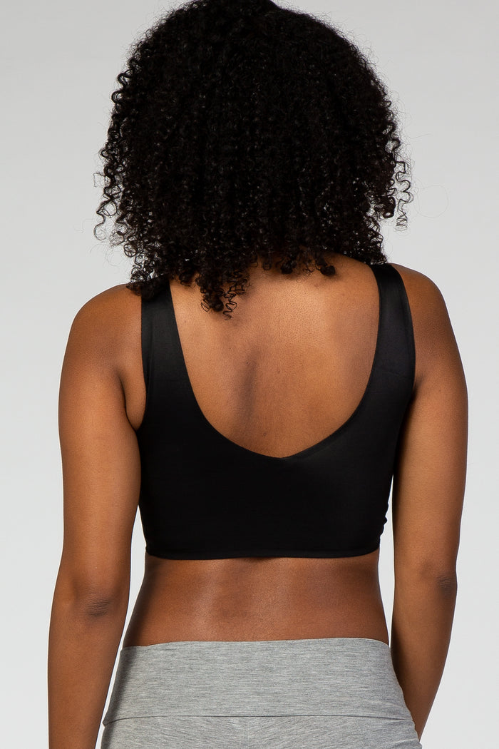 Back view of a woman with curly hair wearing a black scoop neck sports bra and grey leggings