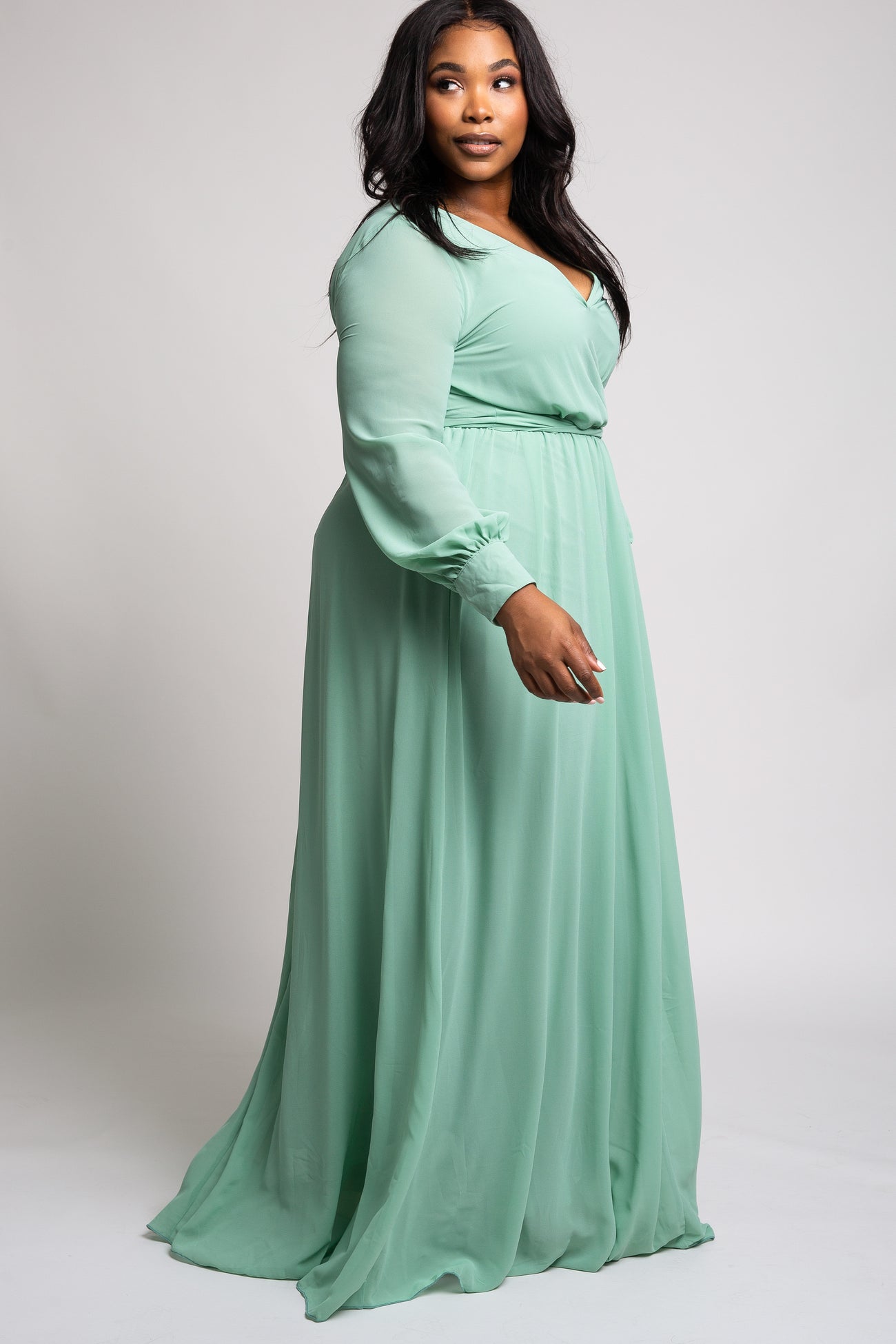 plus size woman wearing a long sleeve mint green maxi dress with a v-neckline and cinched waist