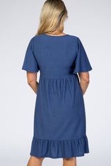 back view of a woman wearing a navy blue maternity dress with short sleeves and a ruffled hem