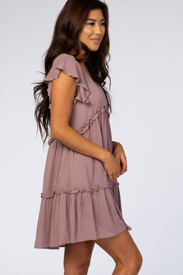 woman wearing a mauve ruffle sleeve tiered maternity dress against a white background