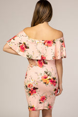 Back view of a woman wearing a light pink off-the-shoulder floral ruffle maternity dress