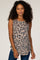 woman with curly hair wearing a tan and black leopard print sleeveless tank top and blue jeans
