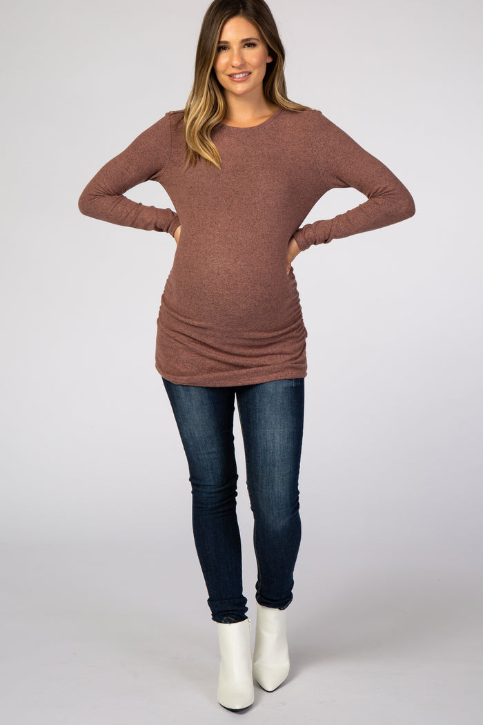 pregnant woman wearing a mauve long sleeve maternity tunic top and dark blue jeans with white boots