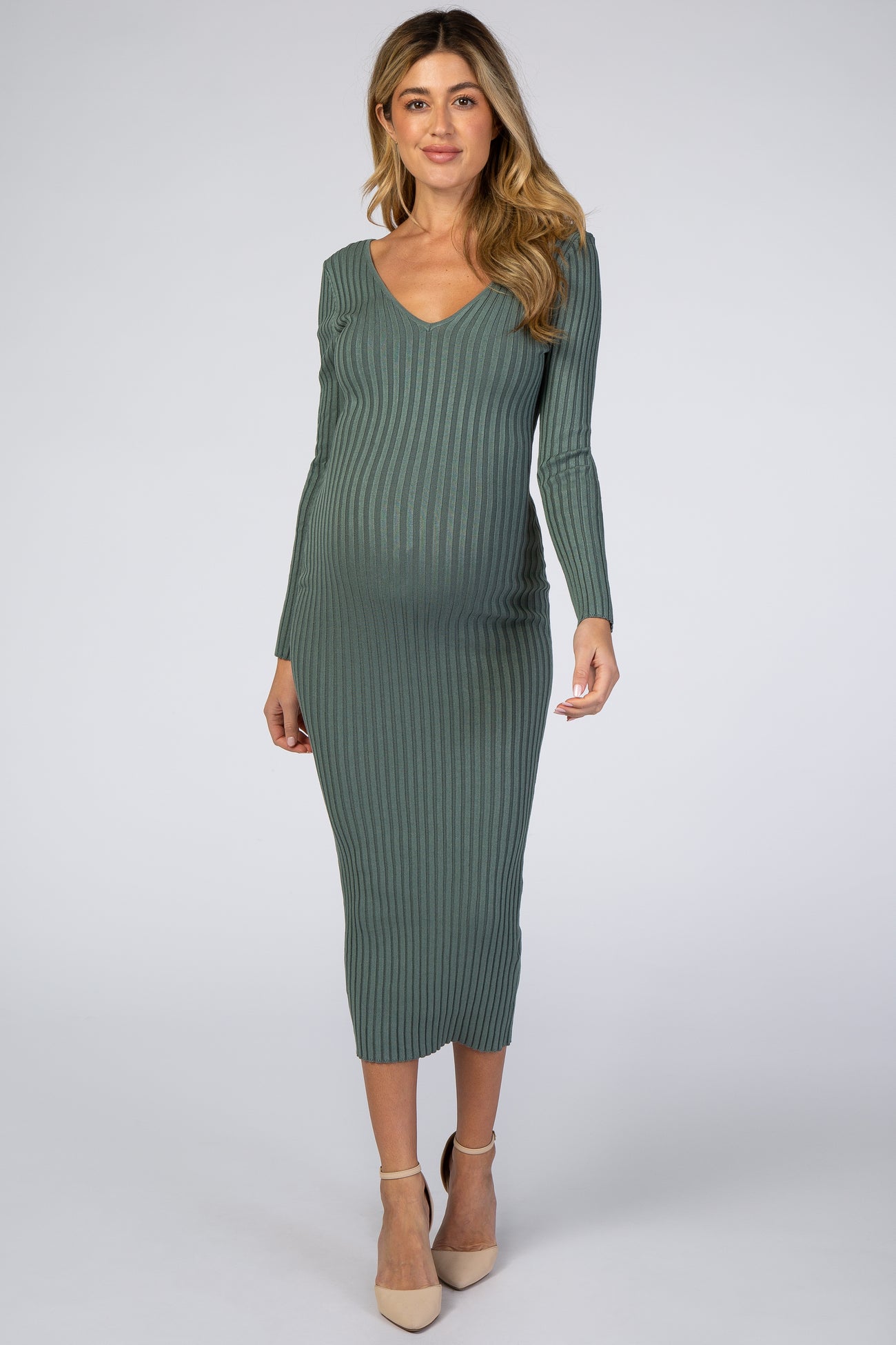 woman wearing a green ribbed maternity midi dress with a v-neck and long sleeves, showcasing her baby bump