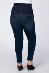 Back view of dark wash maternity skinny jeans with a belly band and frayed hems on a white background