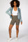 woman wearing olive green ribbed biker shorts with a white tank top and light wash denim jacket