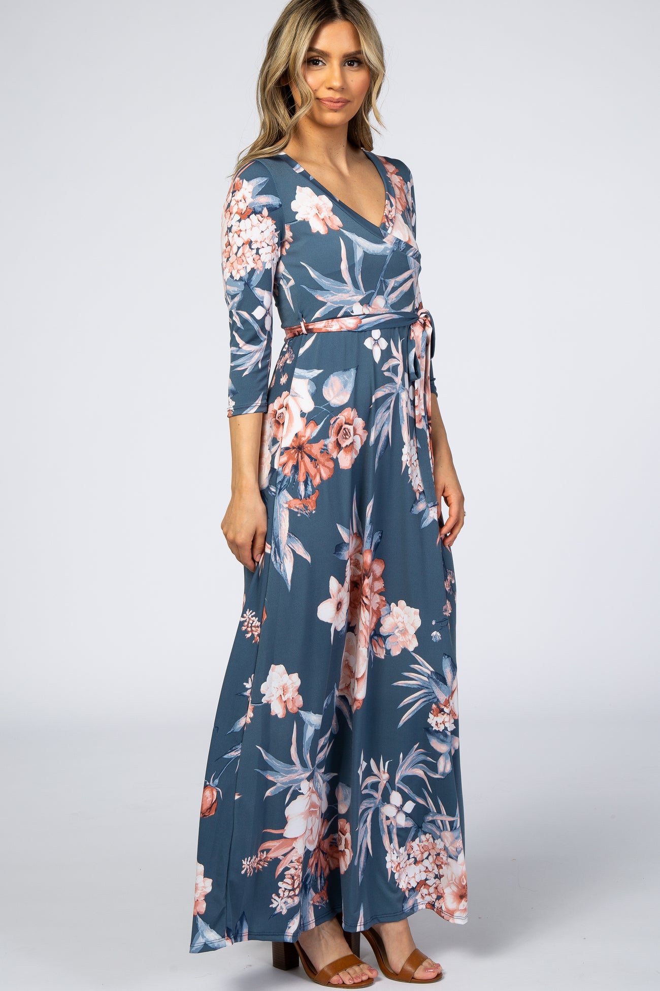 woman wearing a blue floral wrap maxi dress with three-quarter sleeves and a waist tie