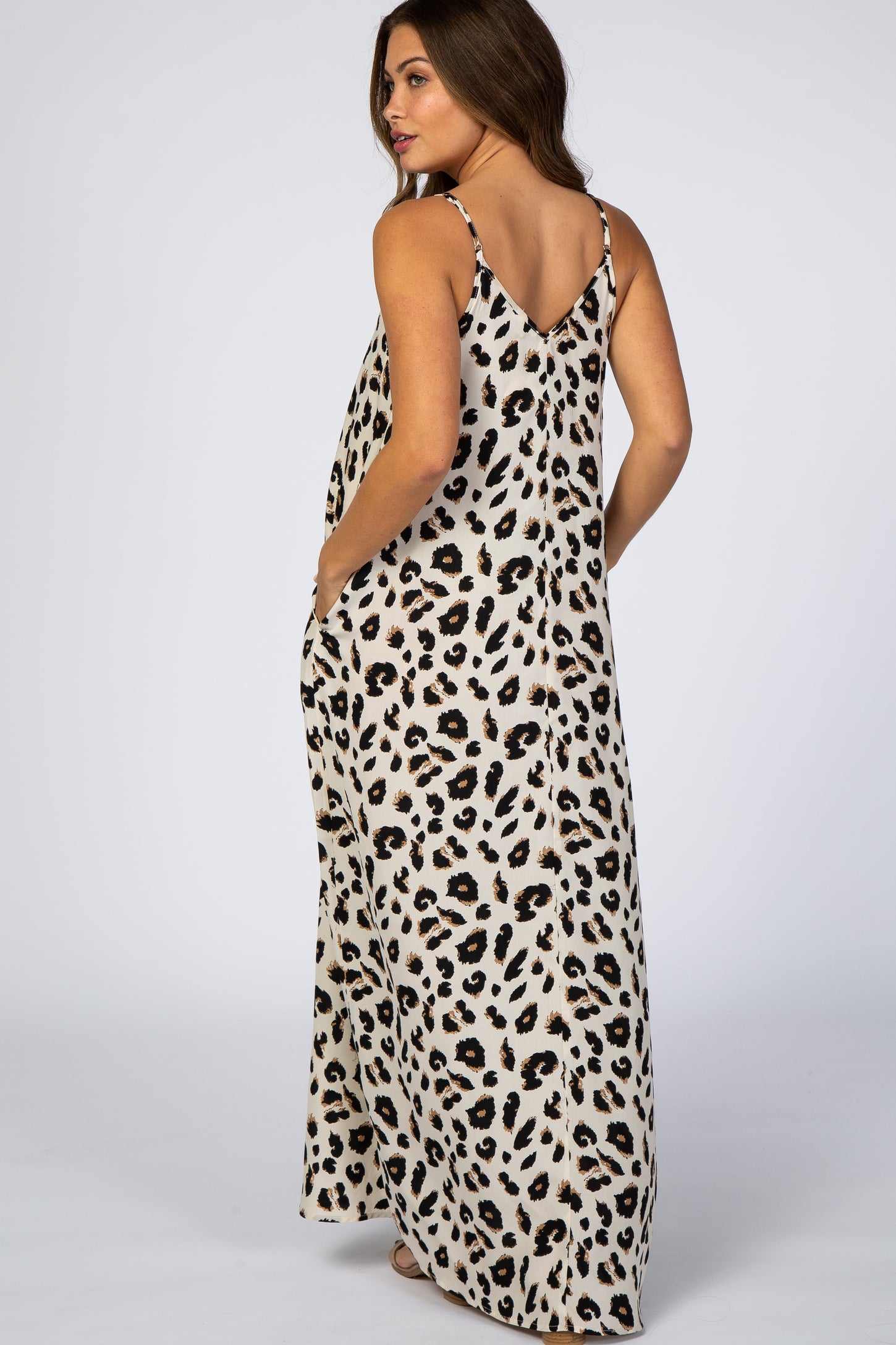woman wearing a sleeveless leopard print maxi dress with pockets and thin straps