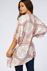 woman wearing a patterned maternity tunic with a loose fit and tied back detail, styled with dark jeans