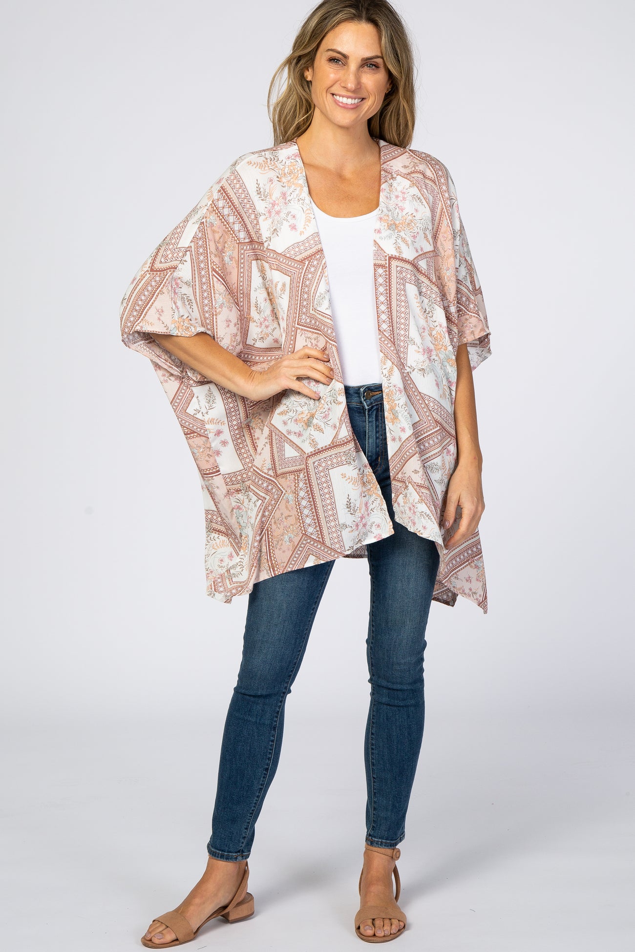 woman wearing a floral print kimono cardigan over a white tank top and blue skinny jeans