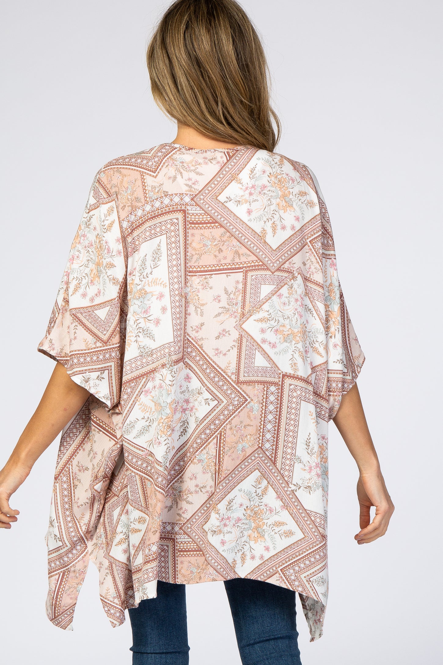 woman wearing a floral patterned oversized kimono-style top in soft tones, with a loose fit and wide sleeves