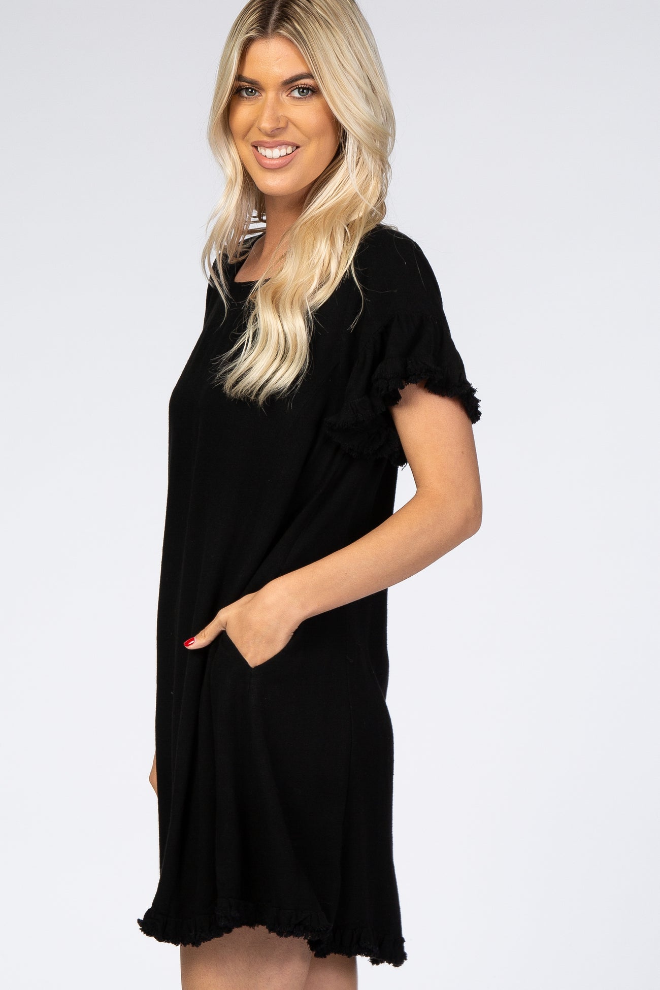 blonde woman wearing a black short sleeve shift dress with fringe trim and side pockets