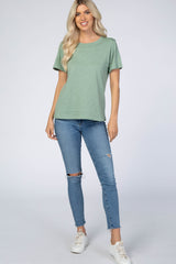 woman wearing a sage green short sleeve t-shirt and distressed blue skinny jeans with white sneakers