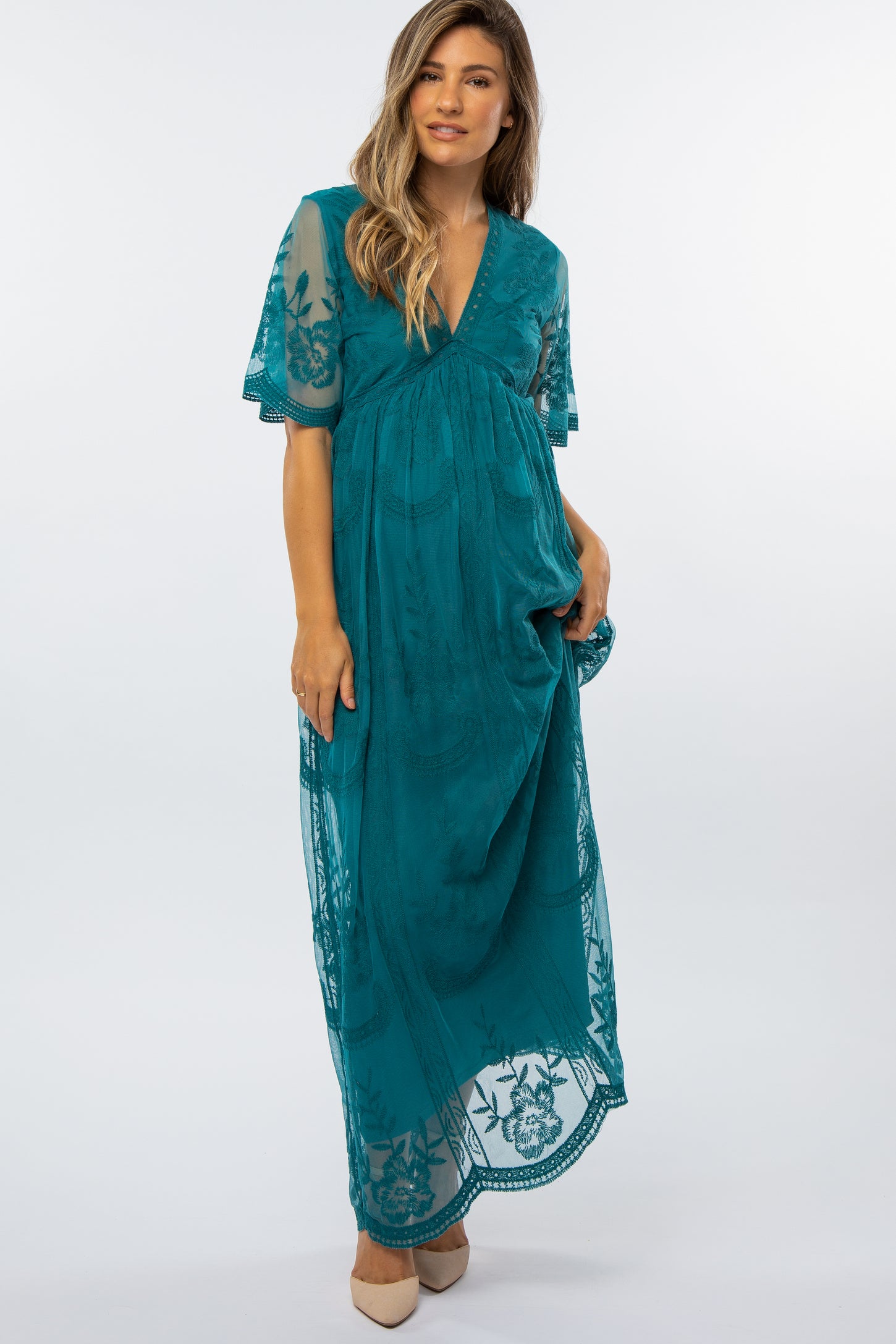 woman wearing a teal lace maternity maxi dress with short sleeves and a v-neckline, featuring a flowing silhouette and baby bump visible