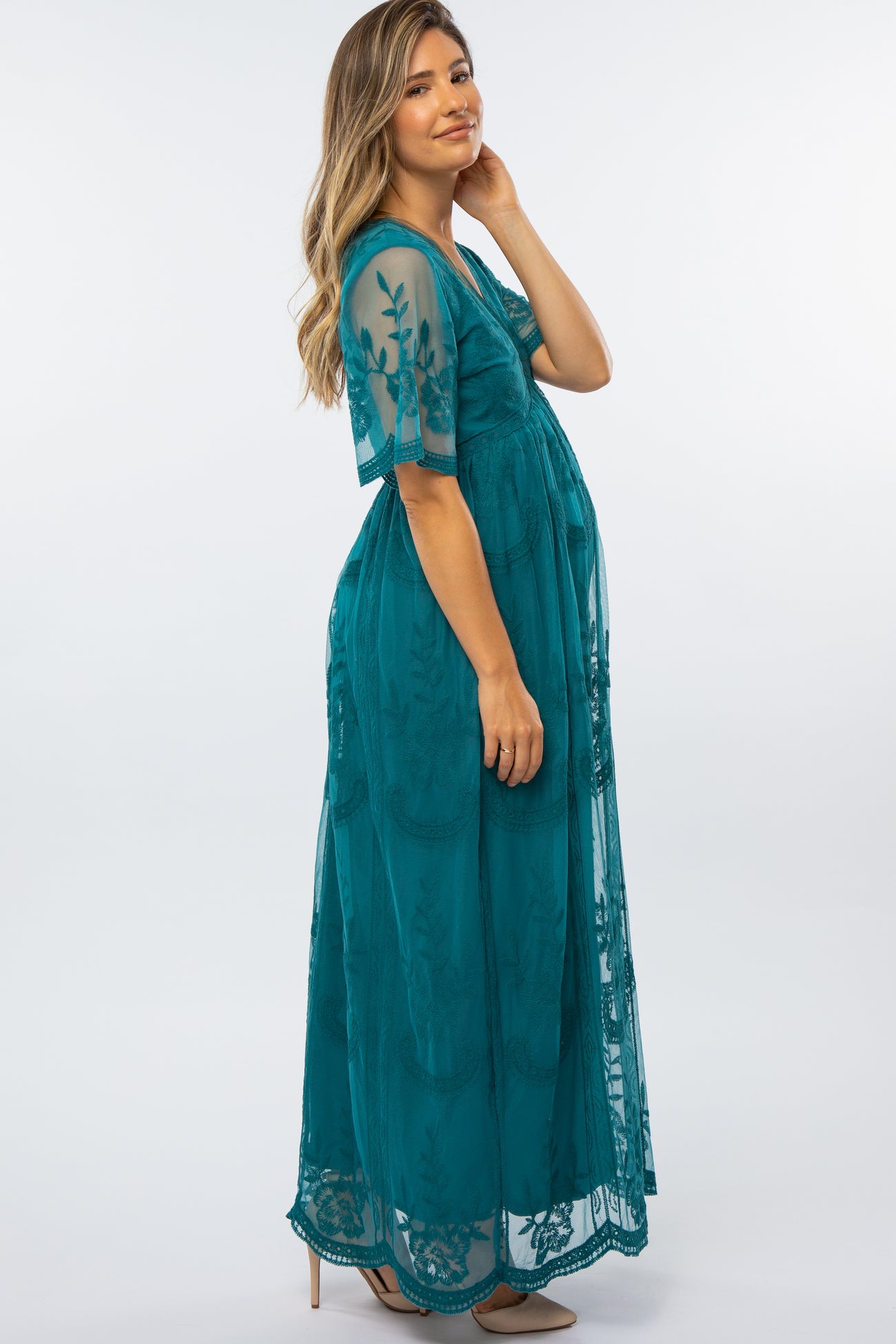 woman wearing a teal floral lace maternity maxi dress and showing her baby bump