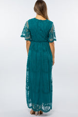 woman wearing a teal maternity maxi dress with short lace sleeves, showing the back view and flowing silhouette