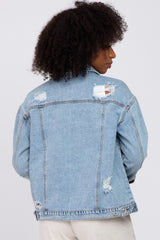 Back view of a woman wearing a light wash distressed denim jacket with ripped details and frayed edges