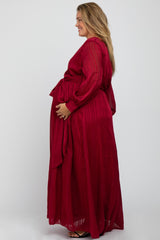 Pregnant woman wearing a long sleeve burgundy pleated maternity maxi dress with a waist tie