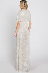 woman wearing a silver sequin evening gown with short flutter sleeves and a flowing skirt, viewed from the back