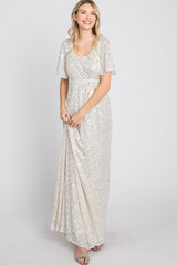 woman wearing a shimmering silver sequin maxi dress with short flutter sleeves and a fitted waist