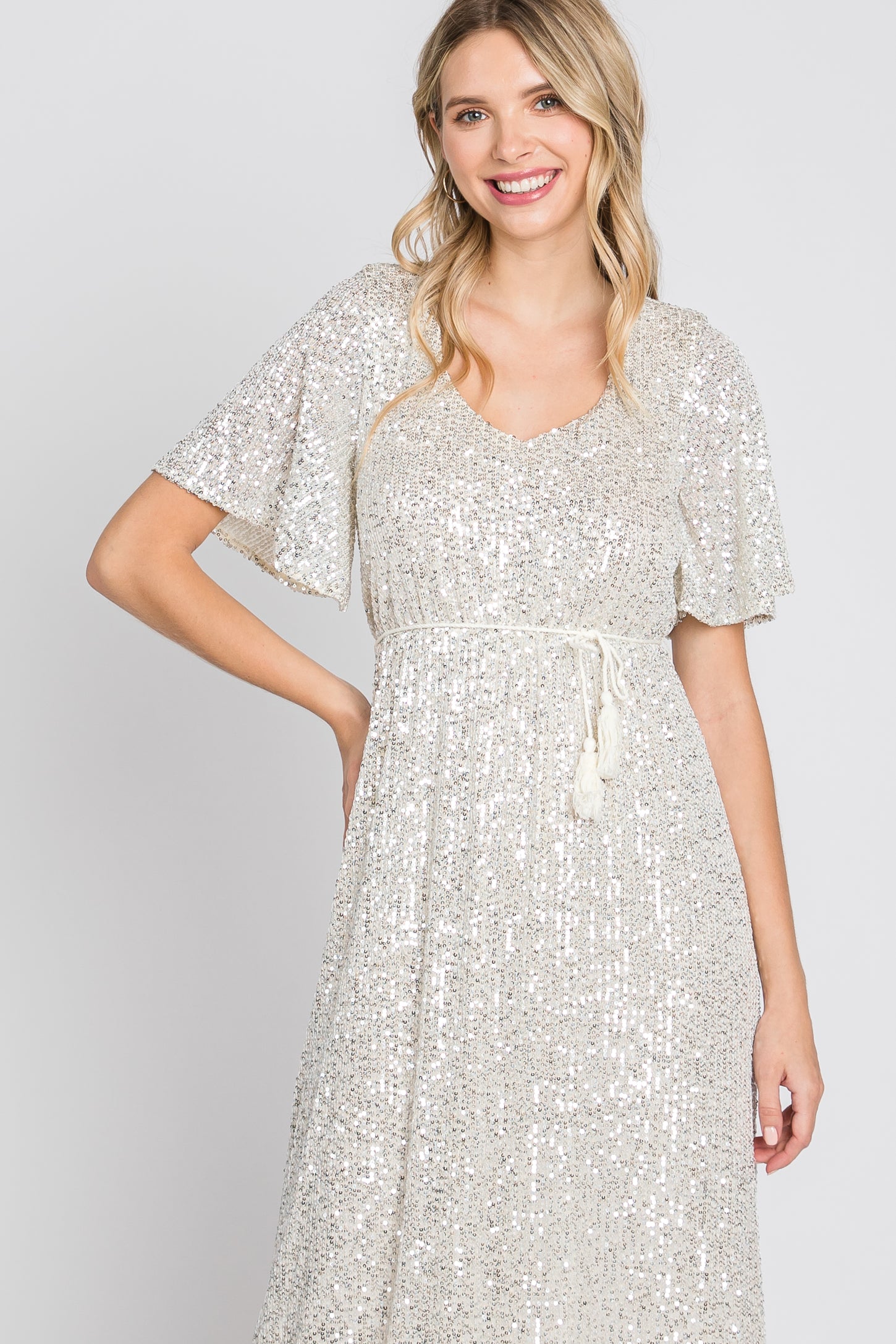 woman wearing a silver sequin dress with short flutter sleeves and a drawstring waist