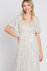 woman wearing a silver sequin dress with short flutter sleeves and a drawstring waist