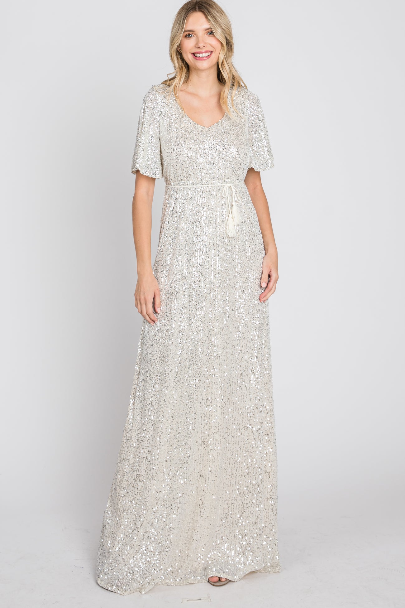 woman wearing a silver sequined maxi dress with a v-neckline and short flutter sleeves