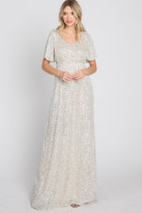 woman wearing a silver sequin maxi dress with flutter sleeves and a fitted waist