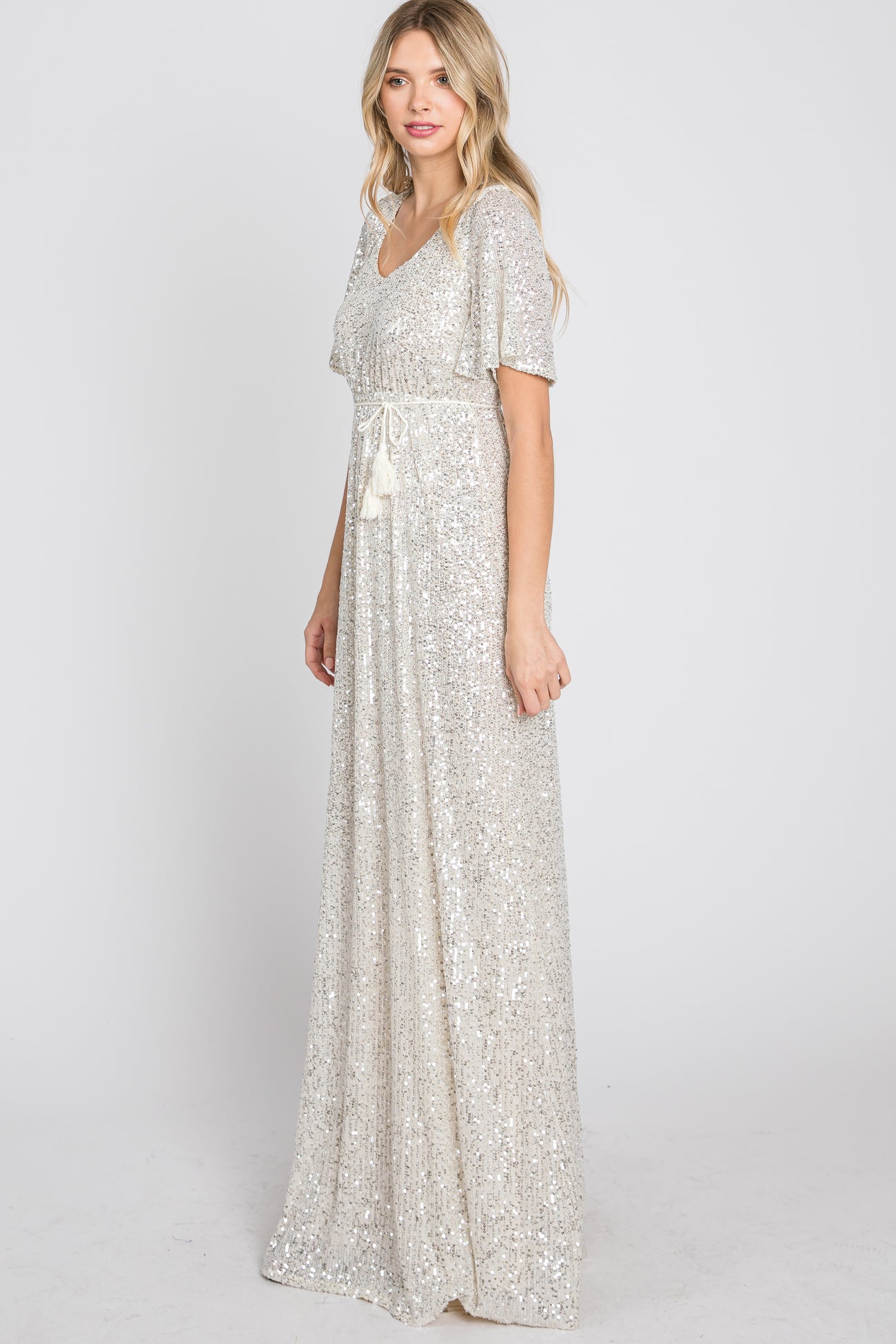 woman wearing a shimmering silver sequin maxi dress with a v-neckline and short flutter sleeves