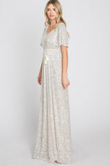 woman wearing a shimmering silver sequin maxi dress with a v-neckline and short flutter sleeves