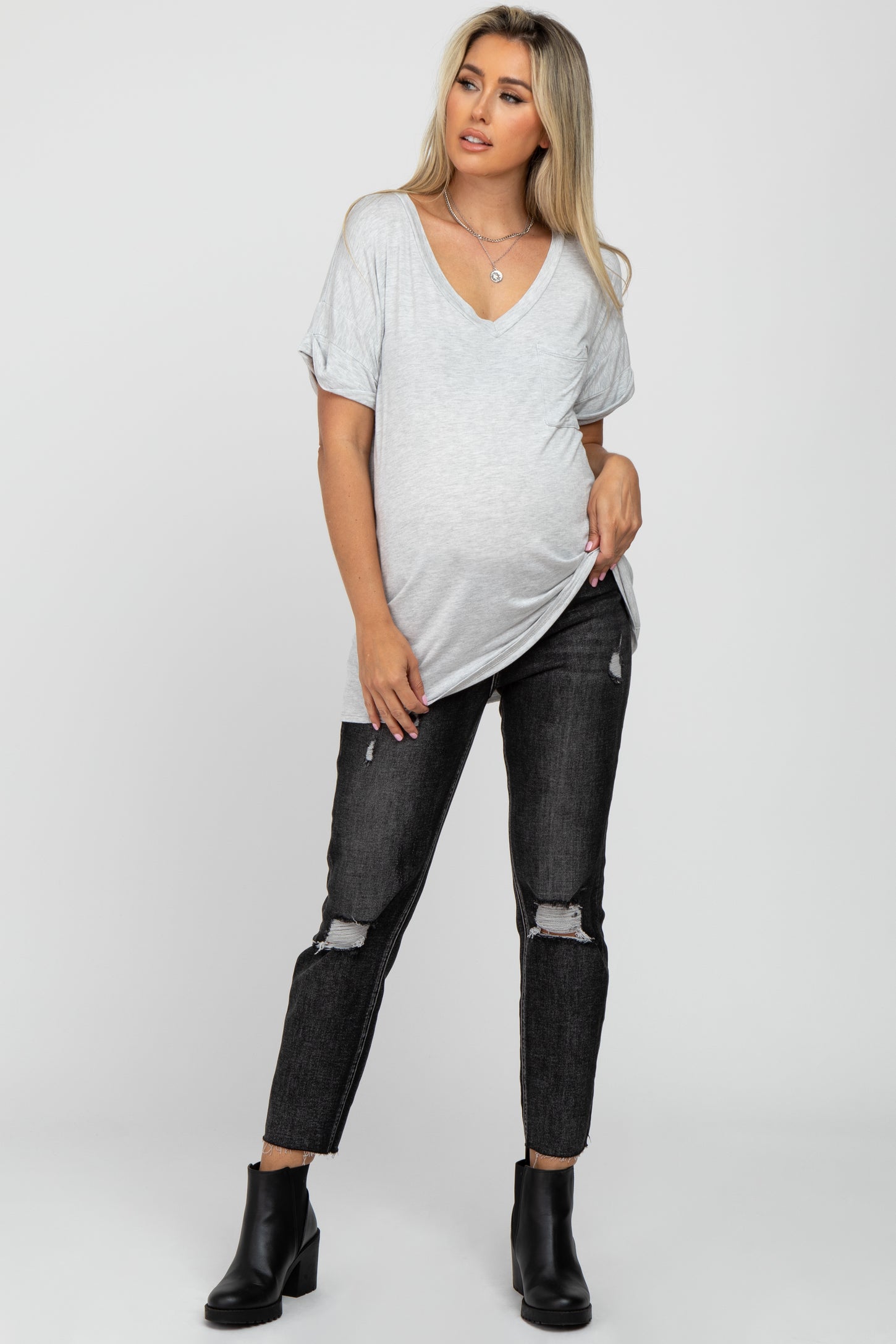 pregnant woman wearing a grey v-neck maternity t-shirt and black distressed jeans with ankle boots