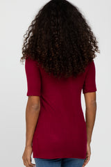 back view of a woman with long curly dark hair wearing a maroon short sleeve t-shirt and blue jeans