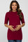 smiling woman wearing a burgundy mock neck maternity top with elbow length sleeves