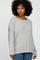 woman with curly hair wearing a light grey oversized knit sweater and blue jeans