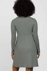 Back view of a woman with curly hair wearing a long-sleeved sage green ribbed knit dress