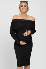 smiling pregnant woman in a black off-the-shoulder maternity dress holding her baby bump