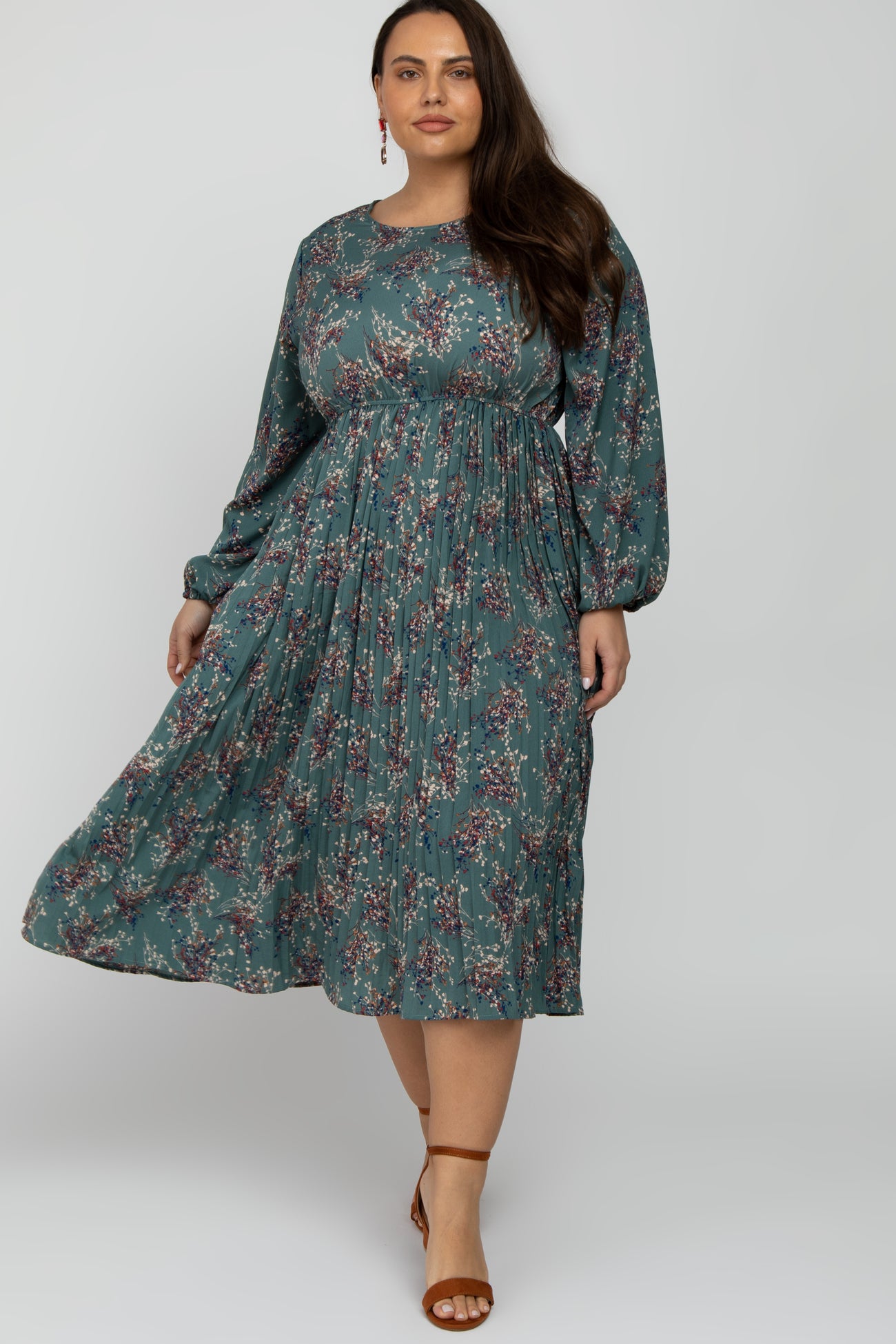 plus size woman wearing a long sleeve teal floral pleated midi dress with brown heels