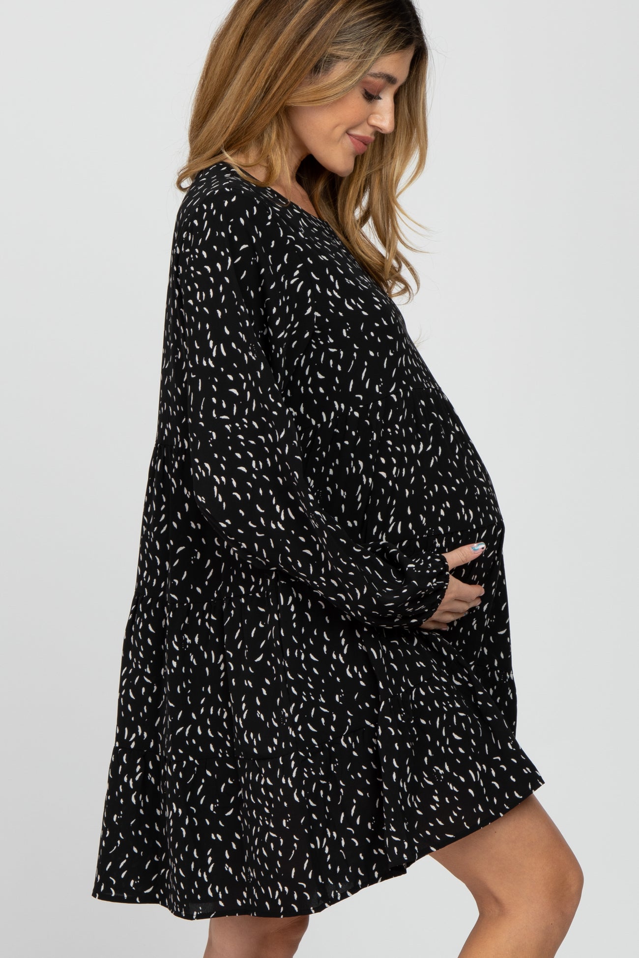 pregnant woman in black and white patterned long sleeve maternity dress holding her baby bump