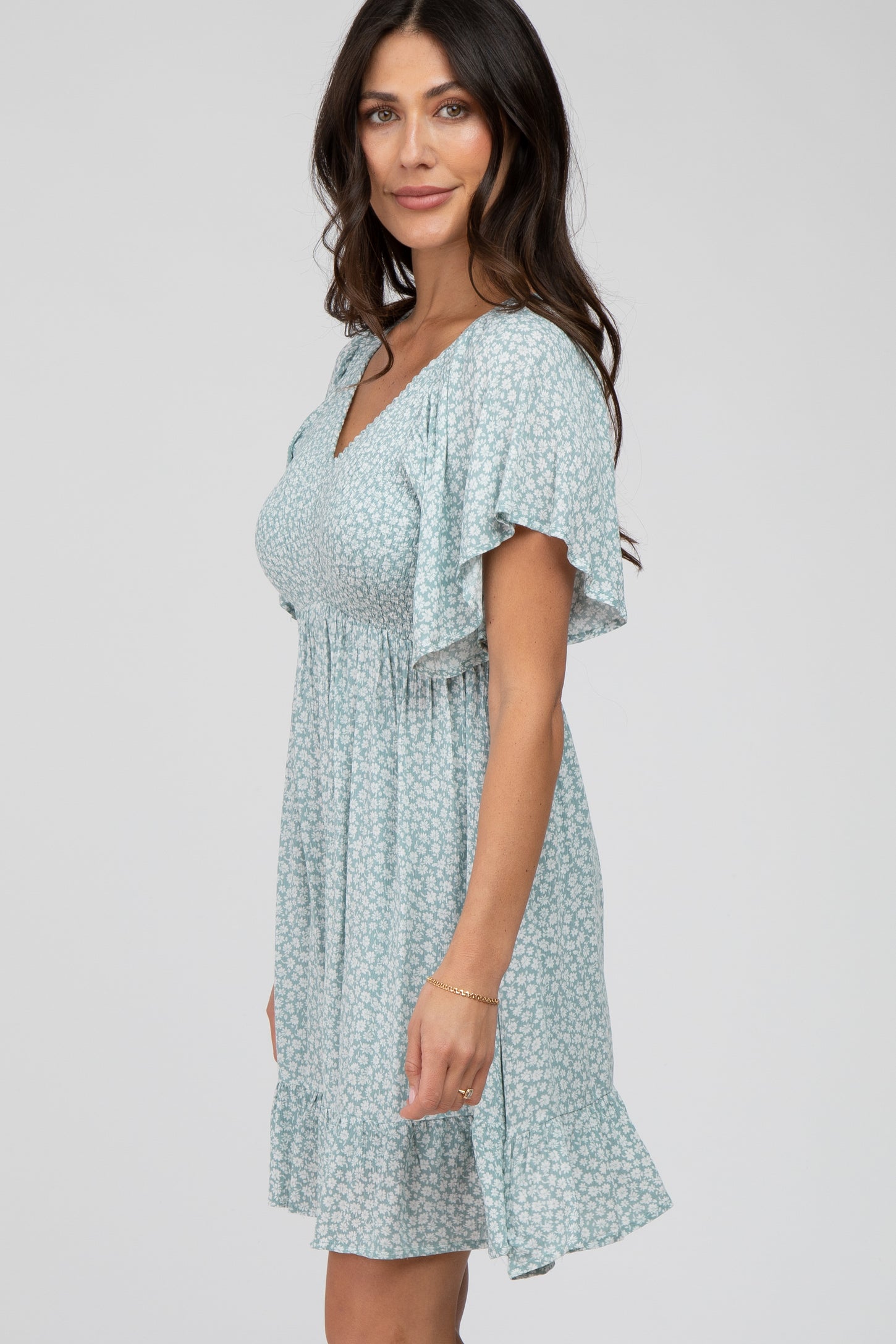woman wearing a light blue floral print maternity dress with flutter sleeves and smocked bodice