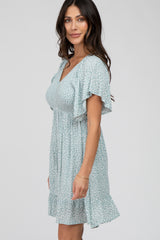 woman wearing a light blue floral print maternity dress with flutter sleeves and smocked bodice