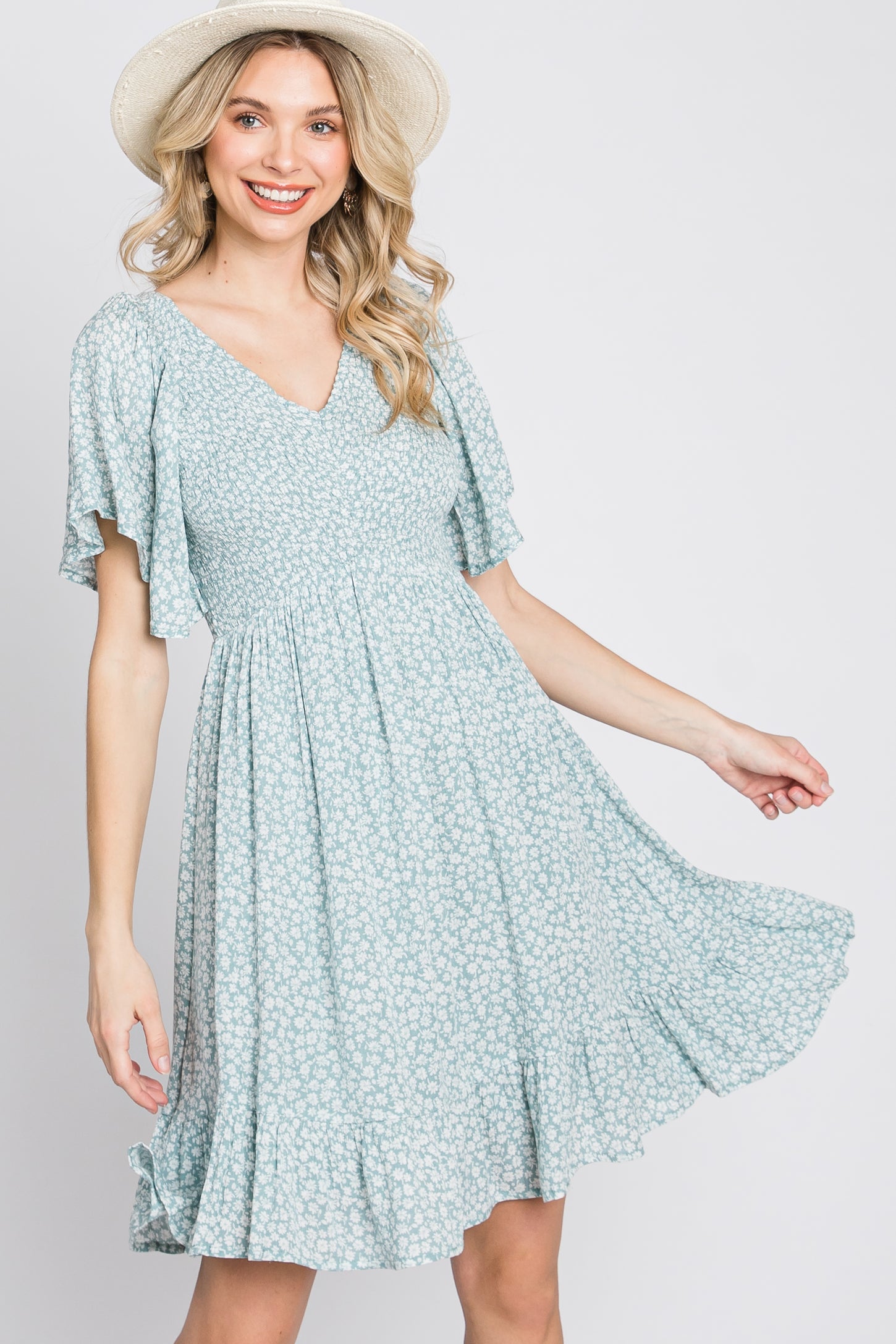 woman wearing a light blue floral print mini dress with flutter sleeves and a straw hat
