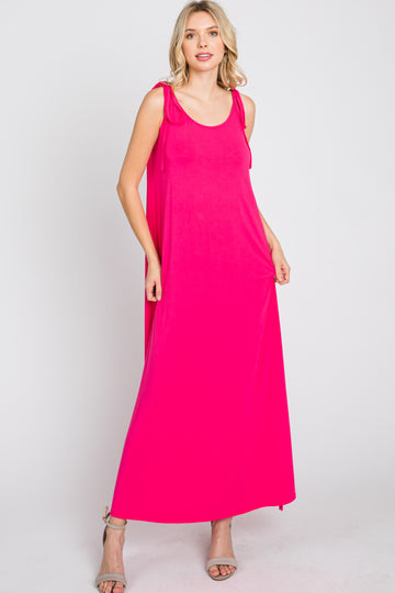 woman wearing a sleeveless hot pink maxi dress with shoulder ties and grey heels against a white background