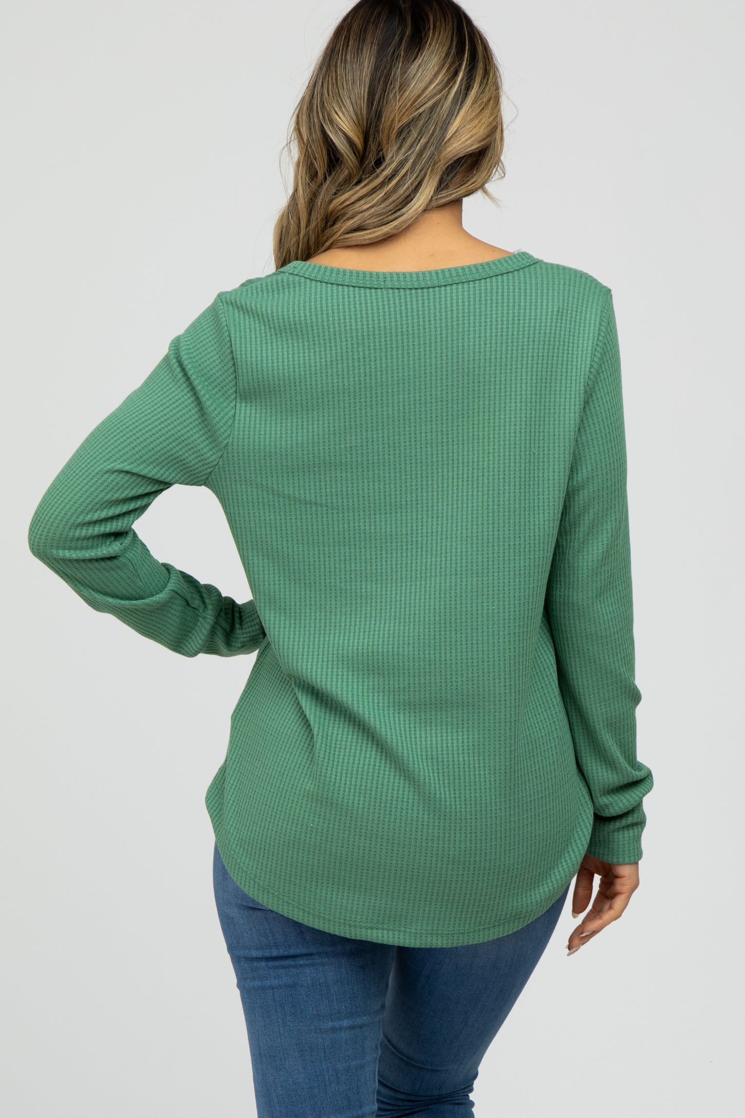 Back view of a woman wearing a green long sleeve waffle knit top and blue jeans