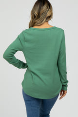 Back view of a woman wearing a green long sleeve waffle knit top and blue jeans