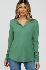 woman wearing a green long sleeve waffle knit henley top and blue jeans