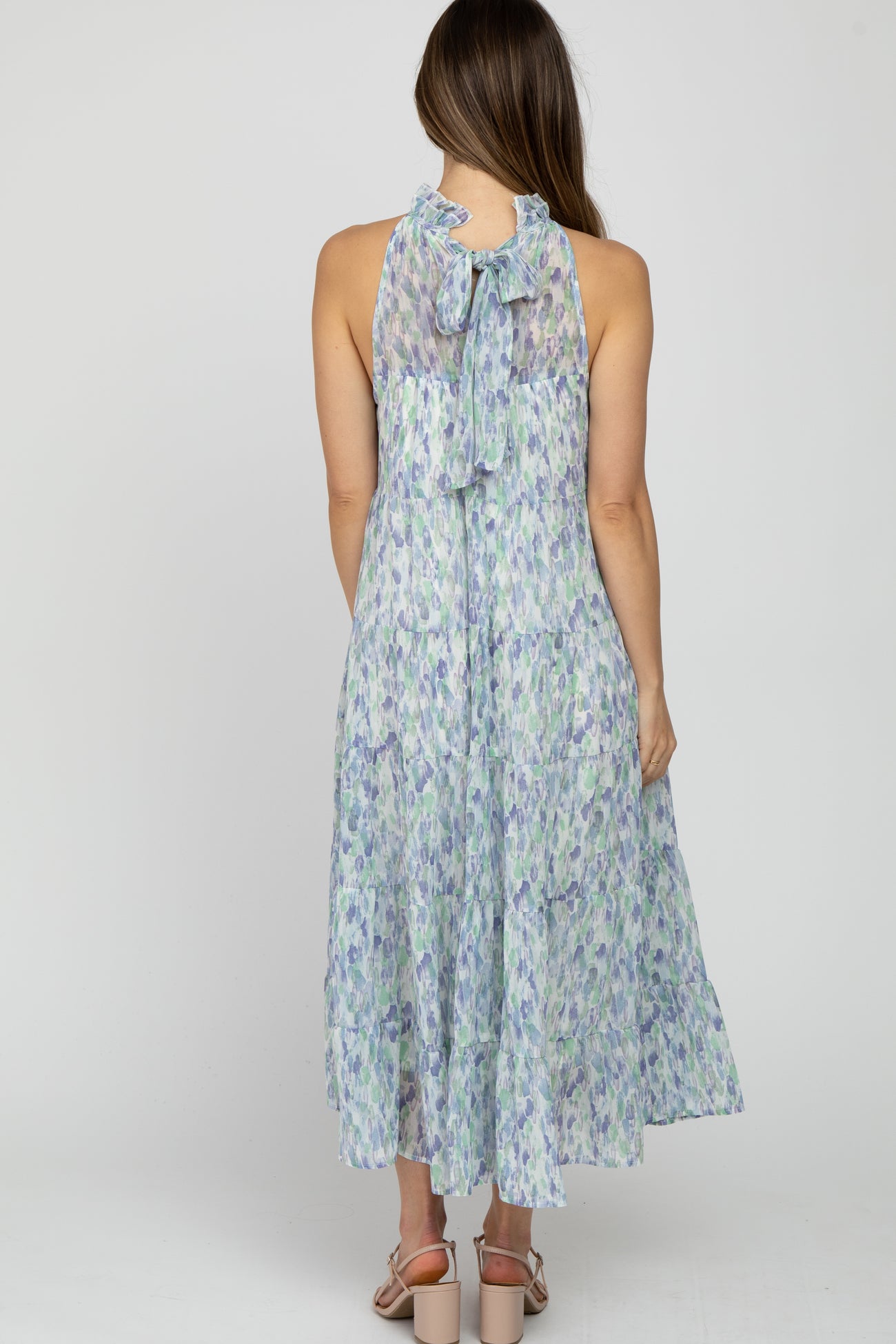 woman wearing a floral print maternity dress with a halter neckline and bow detail at the back