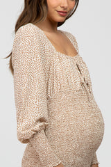 woman wearing a beige maternity dress with a soft animal print and gathered waist, showing her baby bump
