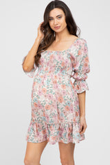 pregnant woman wearing a floral smocked maternity mini dress with puff sleeves and square neckline
